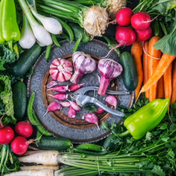 fresh-vegetables-laid-out-in-a-swirl-with-garlic-press-in-middle-canva-600x600